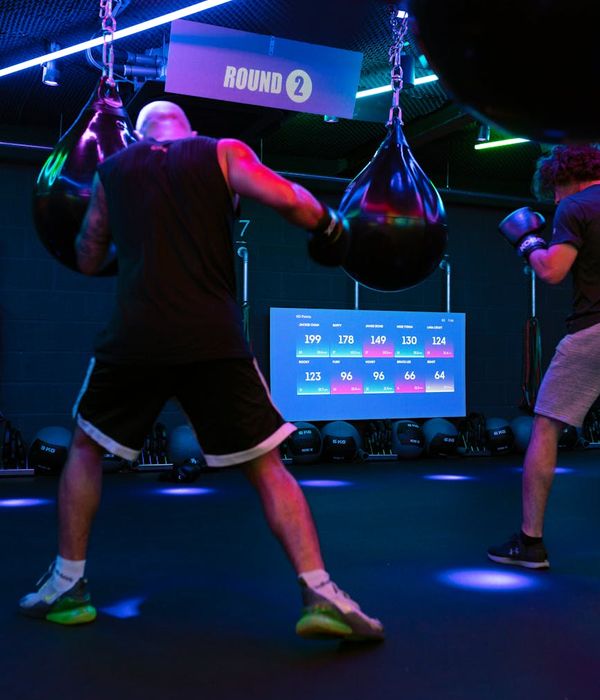 Man performing a strength exercise in a dark, modern gym.
